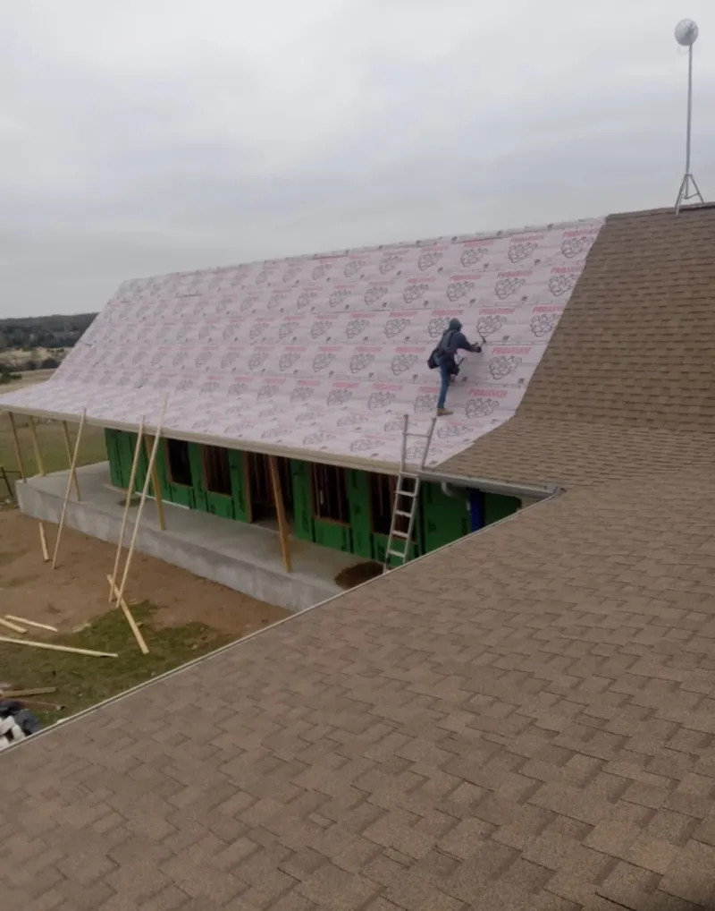 Worker preparing underlayment for a metal roof installation in Adrian